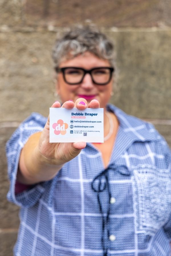 Debbie holding her business card out to the camera